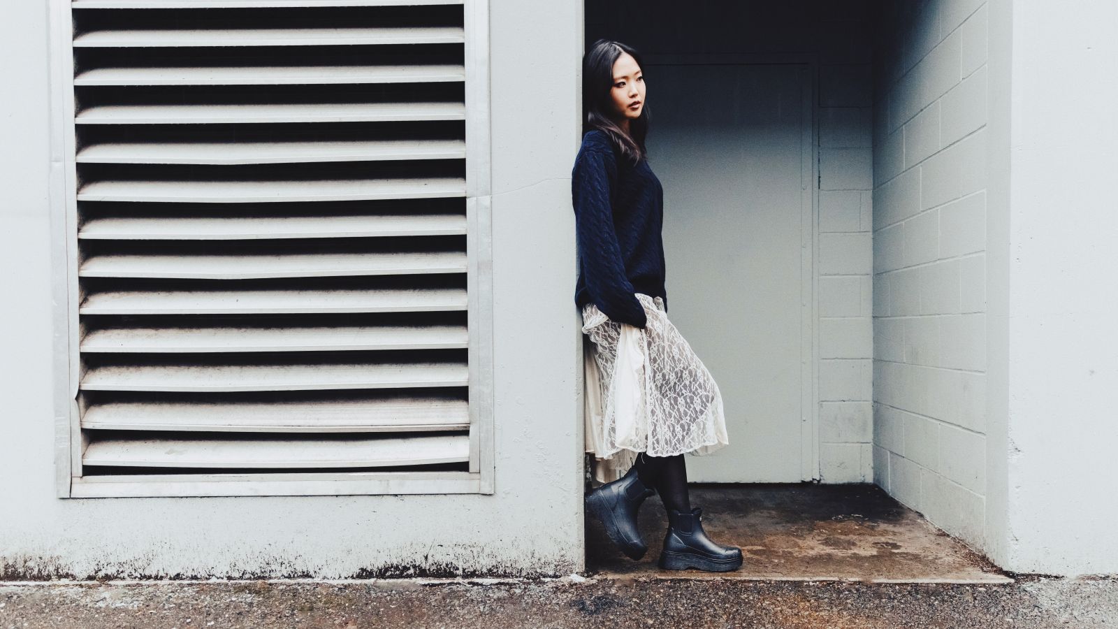 A woman stands in a doorway wearing a the Chooka Upland Platform Chelsea Rain boot.